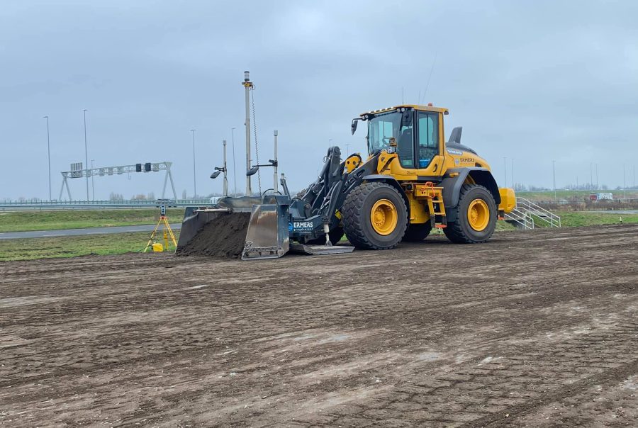 Powerblade aan wiellader met total station langs de snelweg