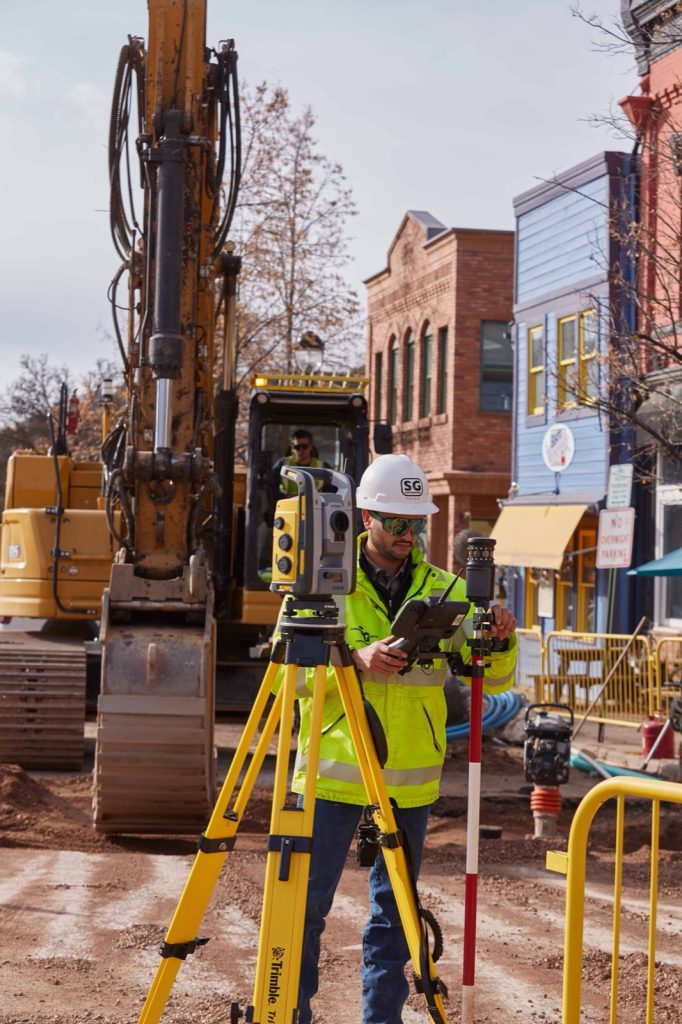 Opstellen van een Trimble total station naast een graafmachine