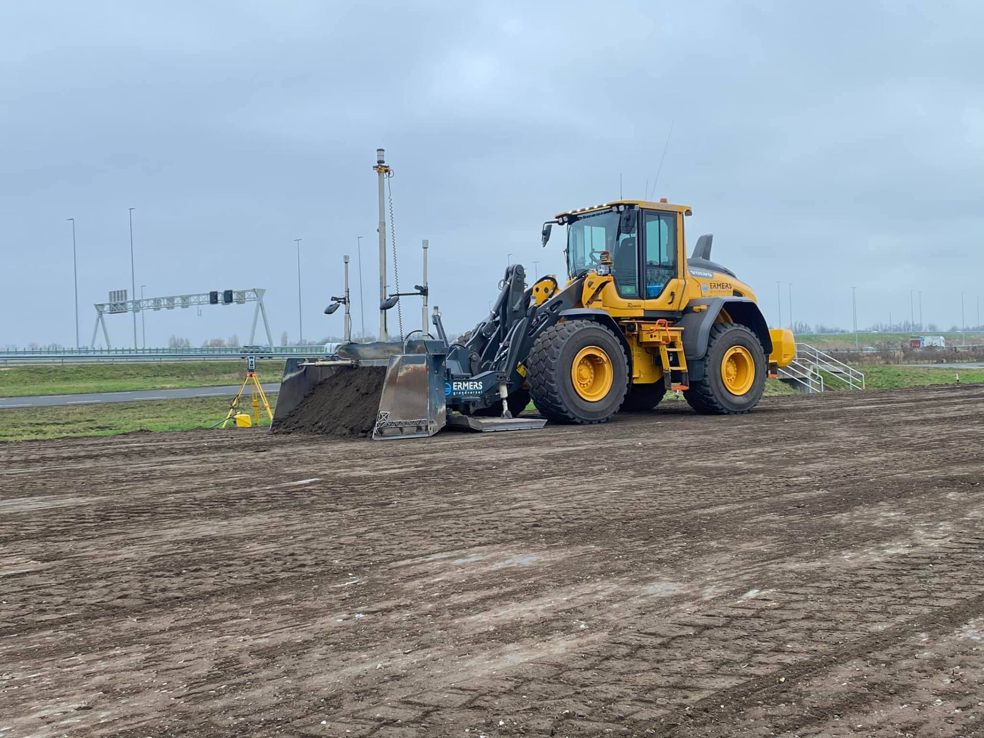 Powerblade op wiellader met total station langs de snelweg
