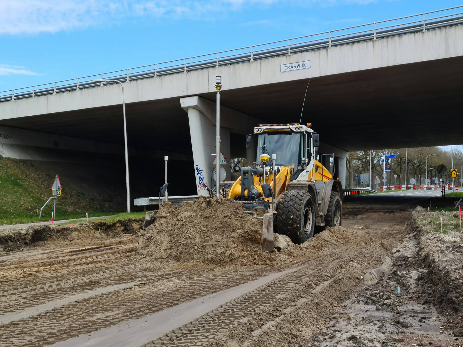 Powerblade aan wiellader met total station-besturing onder een viaduct
